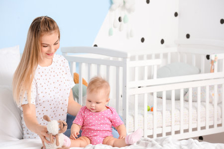 Happy mother playing with cute baby at homeの写真素材