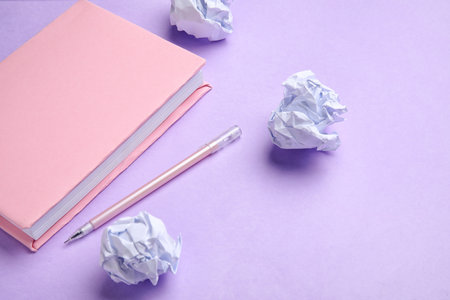 Book, pen and crumpled paper on lilac background. World Poetry Day celebrationの写真素材