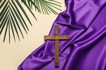 Wooden cross with palm leaves and purple fabric on beige background. good friday conceptの写真素材