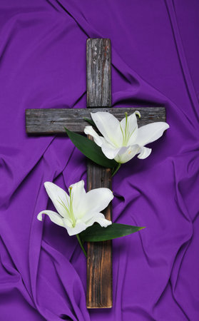 Wooden cross with lily flowers on purple fabric background. good friday conceptの写真素材