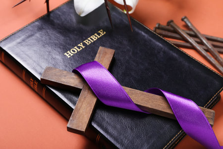 Cross with purple ribbon, Holy Bible and nails on red background, closeup. good friday concept
