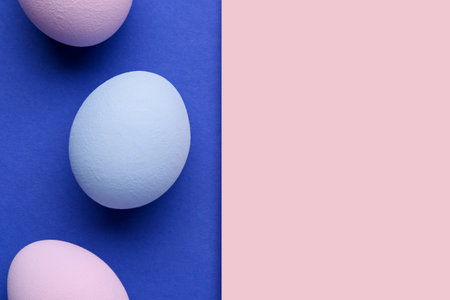 Blank greeting card and painted Easter eggs on blue background, closeupの写真素材