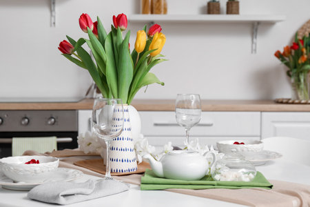 Table setting for International Women's Day celebration with tulip flowers and teapot in interior of roomの写真素材