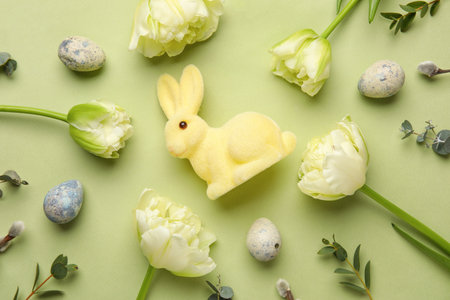 Composition with Easter bunny, painted eggs, tulip flowers and eucalyptus branches on green backgroundの写真素材