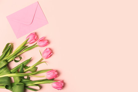 Beautiful tulip flowers and envelope on pink backgroundの写真素材
