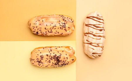 Tasty glazed eclairs on colorful background