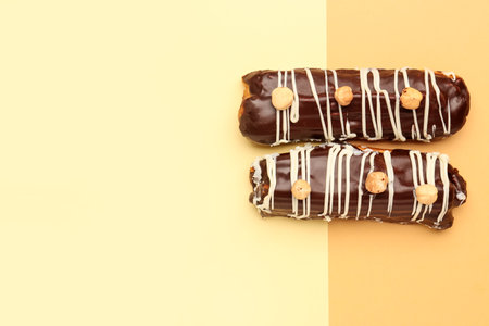 Tasty chocolate eclairs on yellow and orange background