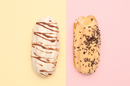 Tasty glazed eclairs on yellow and pink background