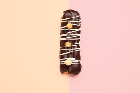 Tasty chocolate eclair on yellow and pink background