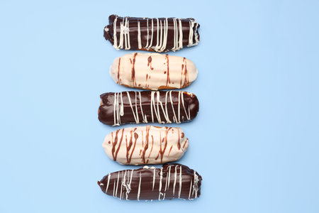 Many delicious eclairs on blue background