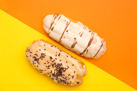 Delicious eclairs on yellow and orange background