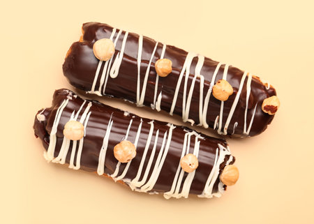 Delicious chocolate eclairs with hazelnuts on beige background