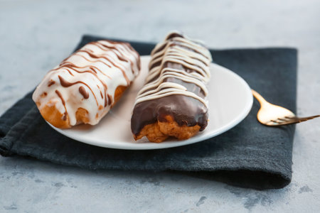 Plate with delicious eclairs on gray table
