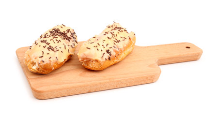 Board with sweet eclairs isolated on white background