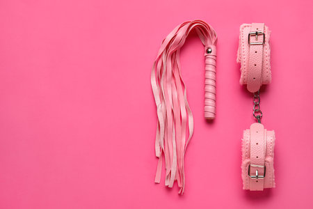 Handcuffs and whip from sex shop on pink backgroundの写真素材