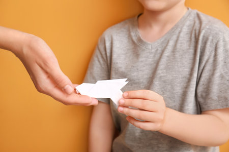 Hands of family with paper dove on color backgroundの写真素材