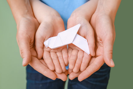 Hands of family with paper dove, closeupの写真素材