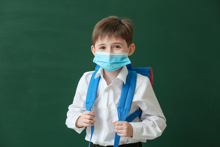 Little schoolboy in medical mask on color background. Coronavirus epidemicの写真素材