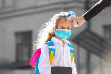Teacher measuring temperature of pupil. Coronavirus epidemicの写真素材