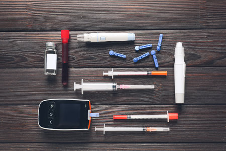 Glucometer, lancet pens, blood sample, syringes and insulin on wooden background. Diabetes conceptの写真素材