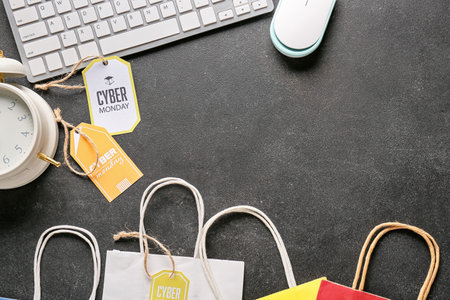 Computer keyboard, alarm clock, shopping bags and tags with text CYBER MONDAY on dark backgroundの写真素材