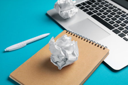 Notebook, pen, laptop and crumpled paper balls on color background, closeup. World Poetry Day celebrationの写真素材