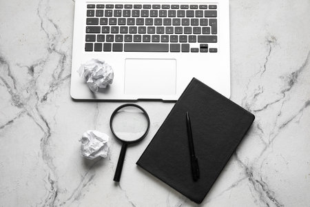 Notebook, pen, magnifier, crumpled paper balls and laptop on light background. World Poetry Day celebrationの写真素材