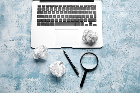 Crumpled paper balls, magnifier, pen and laptop on color background. World Poetry Day celebrationの写真素材