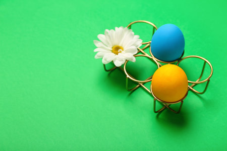 Colorful Easter eggs and chamomile flowers on green backgroundの写真素材