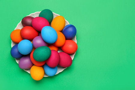 Plate with colorful Easter eggs on green backgroundの写真素材