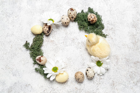 Frame made of Easter quail eggs, baby chicken and chamomile flowers on white grunge backgroundの写真素材