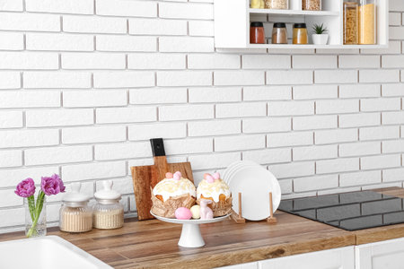Stand with Easter cakes, painted eggs and bunny on kitchen counter