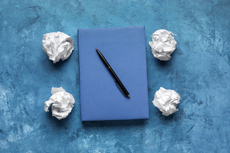 Book, pen and crumpled paper balls on color background. World Poetry Day celebrationの写真素材