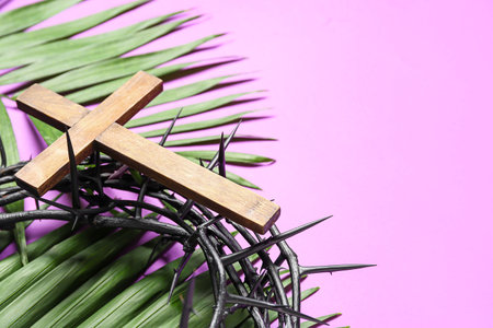 Crown of thorns with wooden cross and palm leaves on lilac background, closeup. good friday conceptの写真素材