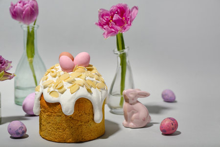 Easter cake, tulip flowers, painted eggs and bunny on gray background