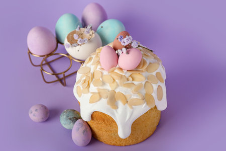 Easter cake, painted eggs and gypsophila flowers on purple background