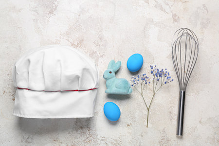 Chef's hat with whisk, flowers, Easter eggs and rabbit on grunge backgroundの写真素材
