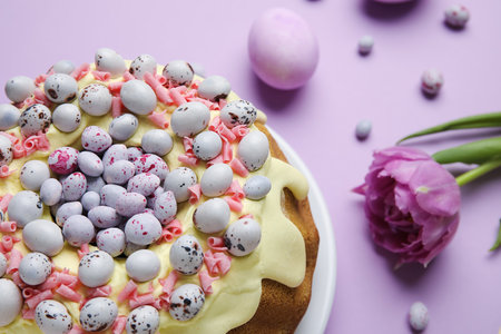 Tasty Easter cake, candies and tulip flower on color background, closeupの写真素材