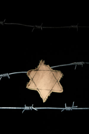 Barbed wire with yellow Jewish badge on dark background.の写真素材