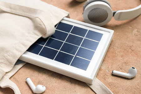 Composition with portable solar panel and wireless earphones on beige grunge backgroundの写真素材