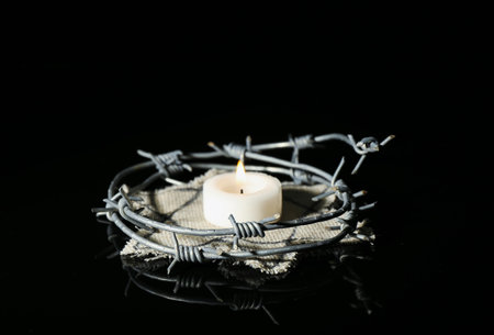 Burning candle with barbed wire and Jewish badge on dark background.の写真素材
