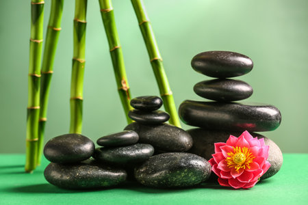 Stack of spa stones, flower and bamboo on green backgroundの写真素材