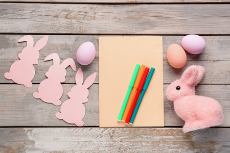 Blank card with pens, Easter eggs and rabbits on wooden backgroundの写真素材