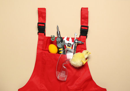 Plumber's uniform with tools, Easter egg and chicken on beige backgroundの写真素材