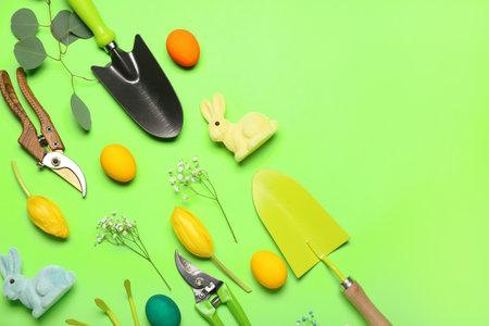 Gardener's tools with Easter eggs, rabbits and flowers on green backgroundの写真素材