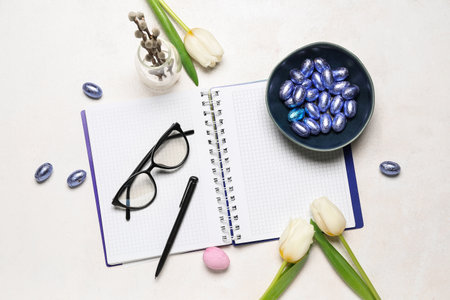 Notebook with eyeglasses, Easter eggs and tulips on white backgroundの写真素材