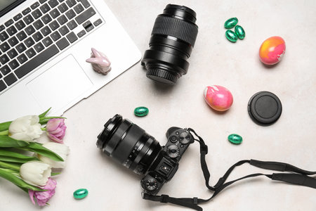 Laptop with professional photo camera, tulips and Easter eggs on white backgroundの写真素材