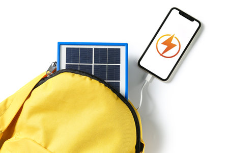 Backpack with portable solar panel charging mobile phone on white background, closeupの写真素材