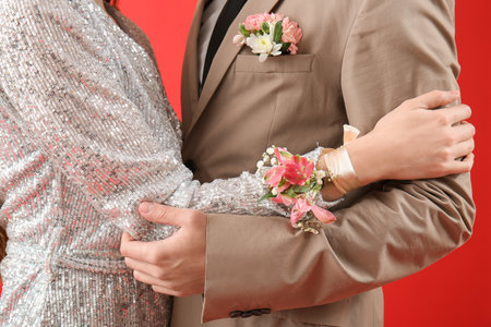 Young girl with corsage and her prom date dancing against red background, closeupの写真素材