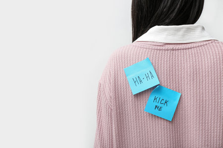 Sticky papers on woman's back against white background, closeup. April Fools' Day celebrationの写真素材